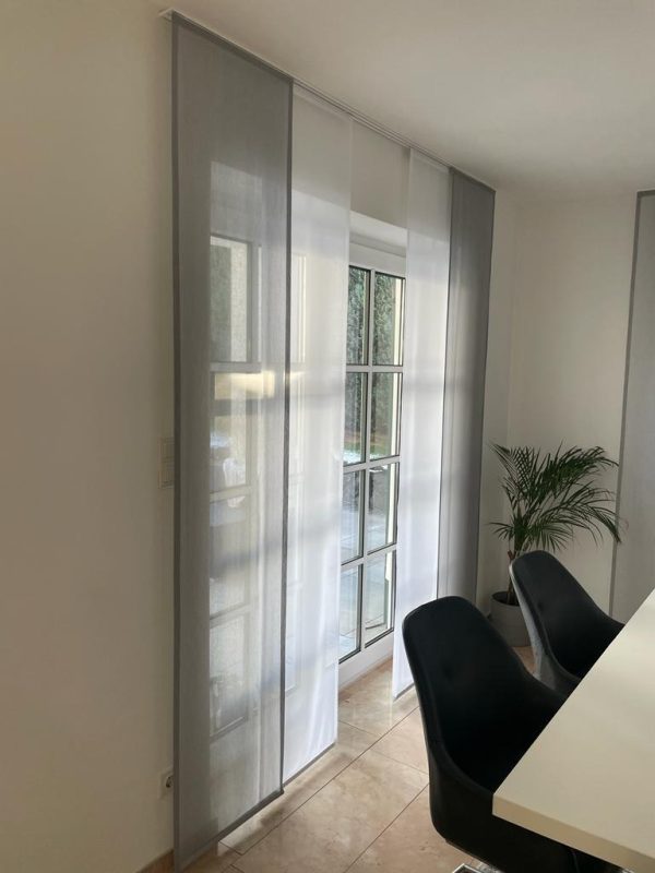 Heller Wohnraum mit bodentiefen Fenstern und maßgefertigten Gardinen von M-Gardinendesign für Sicht- und Lichtschutz.